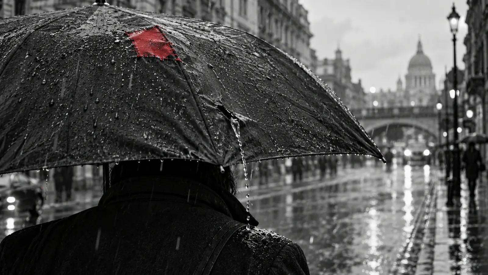 A person walks a rainy monochrome street beneath a worn black umbrella with a vermilion repair, while another split drips onto their shoulder.